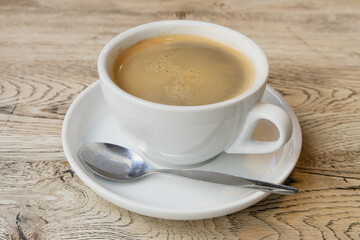 Single cup of black americano coffee on white saucer