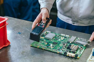 工場でハンディターミナルを使って製品を検査する作業員