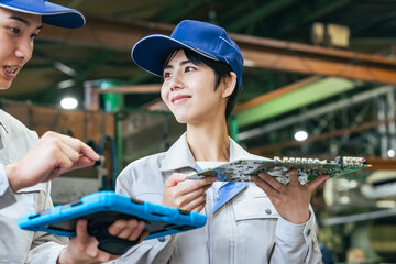 工場でタブレットを使って製品を検査する男女作業員