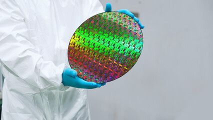 半導体工場でシリコンウエハーを持つ防護服を着た作業員