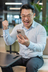 Happy amazed young businessman guy working on smartphone shocked by sudden victory game winning...