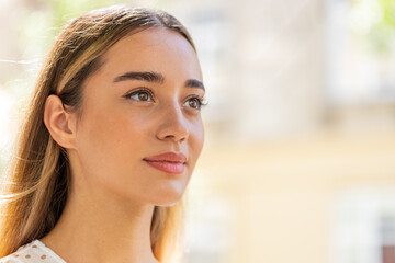 Fototapeta premium Close-up portrait of happy young woman face smiling friendly open eyes glad expression looking away dreaming resting relaxation feel satisfied good news outdoors. Pretty adult lady on city street.