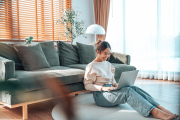Young Asian beautiful woman relaxing on comfortable couch, using laptop at home, happy girl chatting with friends in social network, spending weekend, watching movie, shopping online