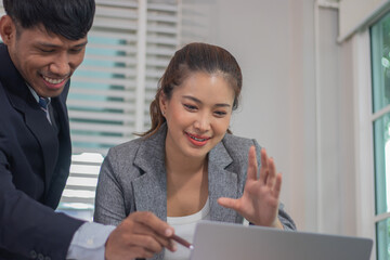 Two professional colleagues, including an Asian businesswoman in a suit, discuss finance, strategy, and marketing in a corporate workplace.
