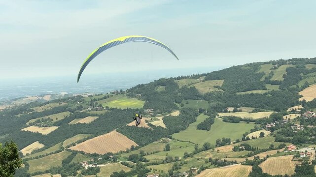 Sestola, Italy &ndash; 05 31 2025: Paraglider flies in the air. Aerial view of paragliding. Paraglider flies above the mountains in a bright sunny day. Concept of extreme sport.
