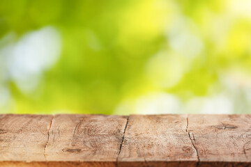 Rustic wooden table with a blurred green nature background perfect for showcasing outdoor food, products, or seasonal promotional content in a natural setting