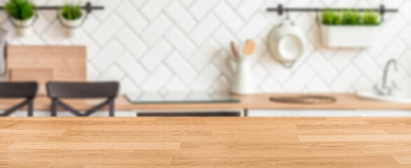 Modern kitchen interior with wooden countertop in focus and blurred background elements including...