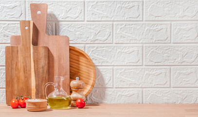 Kitchen scene with wooden cutting boards, olive oil, salt, pepper mill, and fresh tomatoes arranged...
