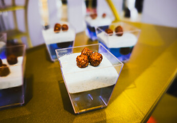 Modern layered dessert in plastic cup with crunchy chocolate topping