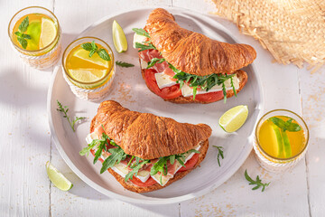 Tasty and homemade french croissant with prosciutto, arugula and camembert.