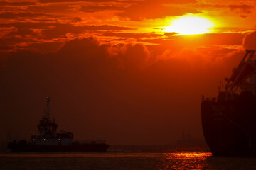 Obraz premium Cargo vessel in the middle of the ocean when it is almost night 