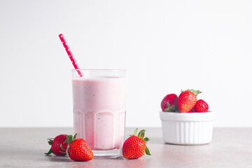 Glass of fresh strawberry milkshake, smoothie and fresh strawberries on white and wooden background. Healthy food and drink concept.