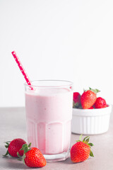 Glass of fresh strawberry milkshake, smoothie and fresh strawberries on white and wooden background. Healthy food and drink concept.