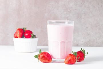 Glass of fresh strawberry milkshake, smoothie and fresh strawberries on white and wooden background. Healthy food and drink concept.