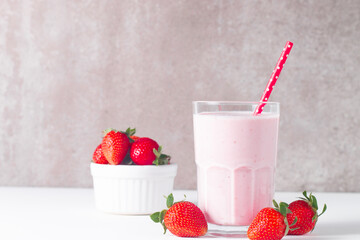 Glass of fresh strawberry milkshake, smoothie and fresh strawberries on white and wooden background. Healthy food and drink concept.