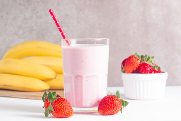 Glass of fresh strawberry milkshake, smoothie and fresh strawberries on white and wooden...