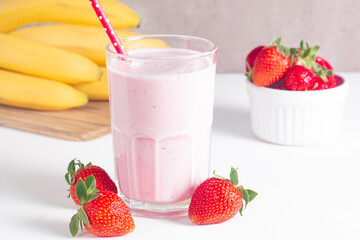 Glass of fresh strawberry milkshake, smoothie and fresh strawberries on white and wooden background. Healthy food and drink concept.