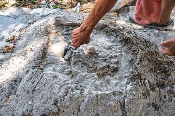 Manual concrete mixing with sand, cement and water, using shovel and trowel on outdoors