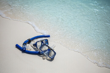 Closeup snorkel gear resting on soft sand calm ocean waves tropical sunny shore. Ideal summer...