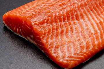 Fresh raw salmon or trout fillet. Fish for sushi. Preparing fish for cooking. Black background. Healthy seafood food.