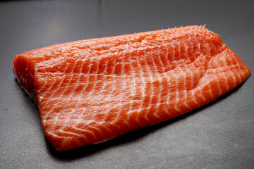 Fresh raw salmon or trout fillet. Fish for sushi. Preparing fish for cooking. Black background. Healthy seafood food.