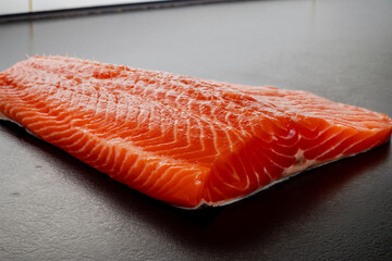Fresh raw salmon or trout fillet. Fish for sushi. Preparing fish for cooking. Black background. Healthy seafood food.
