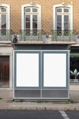 Dual blank billboards on a street-level structure stand in front of a traditional tiled building with ornate balconies, creating a blend of urban advertising and historic Portuguese architecture.