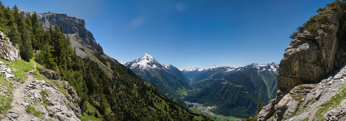 Large panorama in the Swiss mountains with hiking trail and mountain Bristen under blue sky