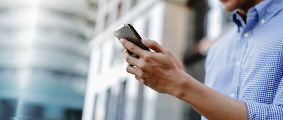 A man using a smartphone in an urban environment, representing mobile communication, digital lifestyle, and business on the go