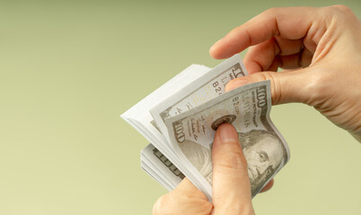 Hands counting US dollar bills, symbolizing finance, payment, banking, and economic transactions