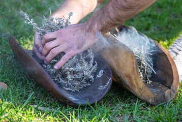 Australian Aboriginal smoking ceremony, human hands and wooden dish with a smoke of burning tree branches, the ritual rite at the community event, symbol of joining to the indigenous culture