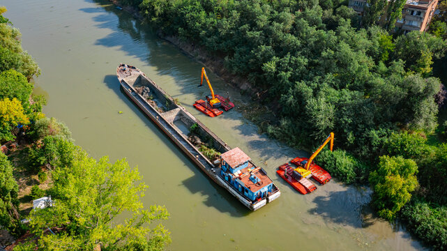 Aerial view of river, canal is being dredged by excavators
