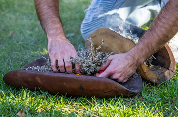 Australian Aboriginal smoking ceremony, human hands and wooden dish with a smoke of burning tree branches, the ritual rite at the community event, symbol of joining to the indigenous culture