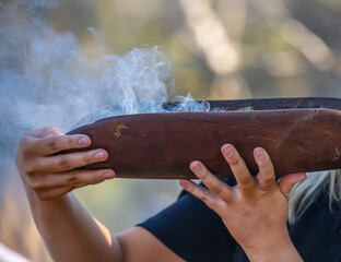 Australian Aboriginal smoking ceremony, human hands and wooden dish with a smoke of burning tree branches, the ritual rite at the community event, symbol of joining to the indigenous culture