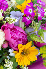 Wrapped flower bouquet made of mixed spring flowers. Beautiful vibrant colored fresh flowers arrangement. Birthday bouquet with peonies and sunflowers.