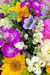Wrapped flower bouquet made of mixed spring flowers. Beautiful vibrant colored fresh flowers arrangement. Birthday bouquet with peonies and sunflowers.