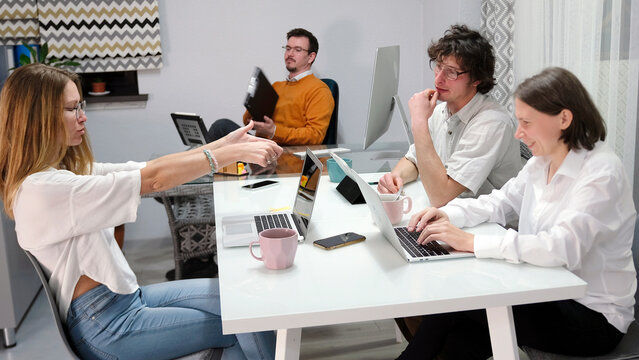 Colleagues discuss the morning news at the beginning of the working day. A group of people is sitting at a table and working on a business project