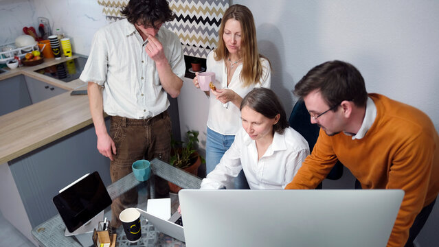 Young specialists in the field of marketing and modern technologies crowded around the head's desk. Business office. Team building