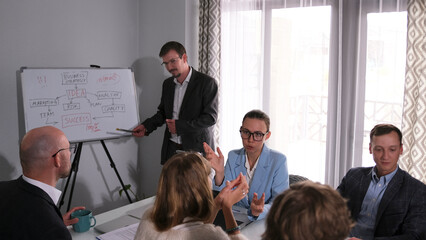 A stylish businesswoman discusses the company's profits and success with colleagues. Several people...