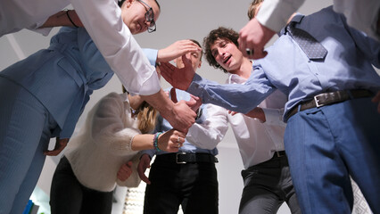 The scene demonstrates camaraderie and teamwork. A group of successful professionals stands in a circle and begins to build a tall tower