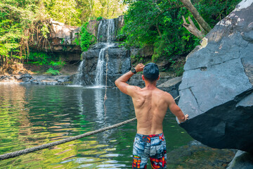 Travel people enjoy beautiful waterfall in tropical rainforest jungle on nature background. Active...