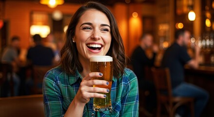 Woman laughing holding a glass of beer. She's sitting at a bar and is happy. Friends and bokeh lights in background add to atmosphere.
