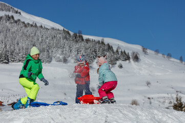 Happy girl and boys have fun snowball fighting on mountain slope