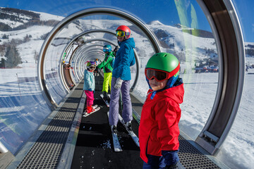 Happy family enjoying skiing in snowy tunnel lift on a sunny day