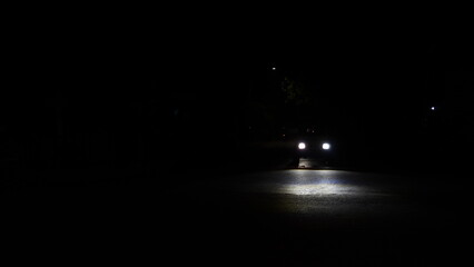 Blurred motion of a vehicle with headlights illuminating the road at night, partially blurred...