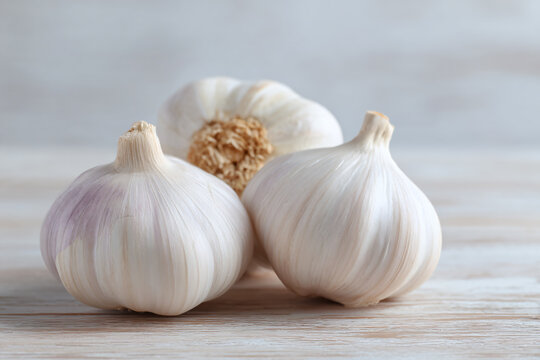 three garlic bulbs on a wooden table