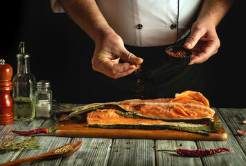 A chef seasons fresh salmon fillets with various spices in a rustic kitchen, showcasing culinary techniques and attention to detail during meal preparation