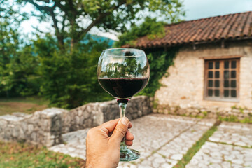 Red Wine Glass in Hand with Stone Cellar Background in France or Italy