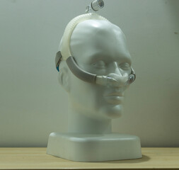 A nasal pillow CPAP mask mounted on a white mannequin head is characterized by transparent, soft...