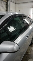 Fototapeta premium Silver Car Gleaming With Water Droplets After A Wash Shiny Vehicle
